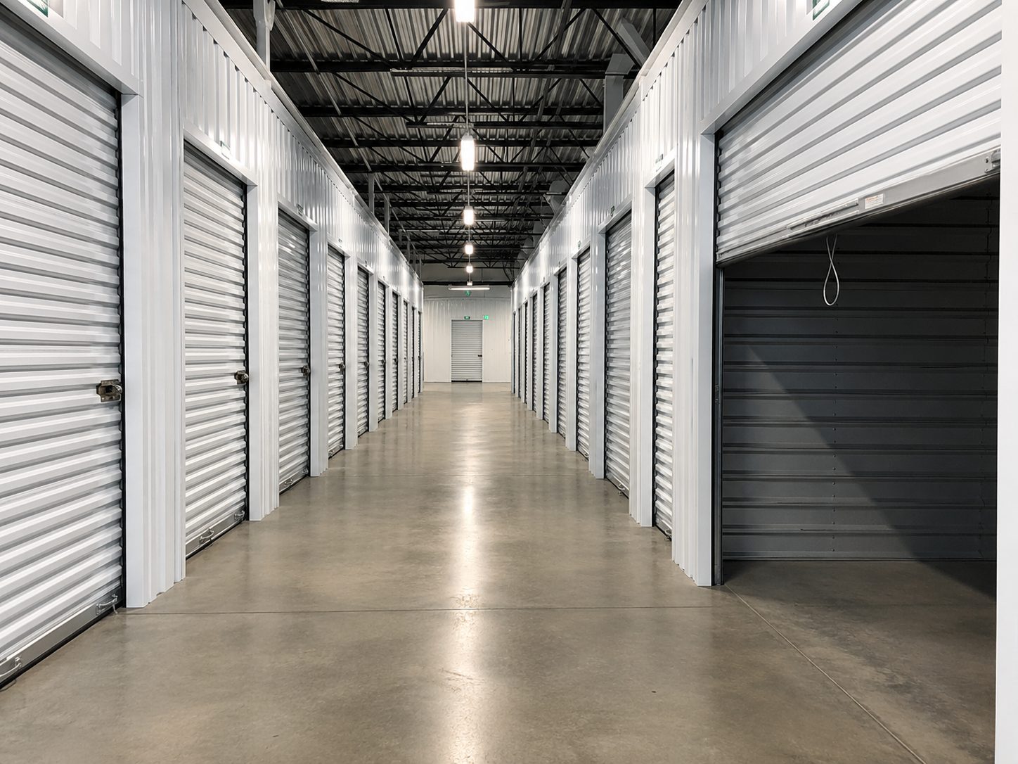 Interior corridor of a clean self-storage facility, rows of white roll-up unit doors